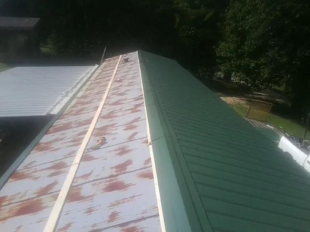 Old rusted panels beside newly installed green metal roofing — Wind Damage Roof Repair by Roofing Brothers in Fairborn