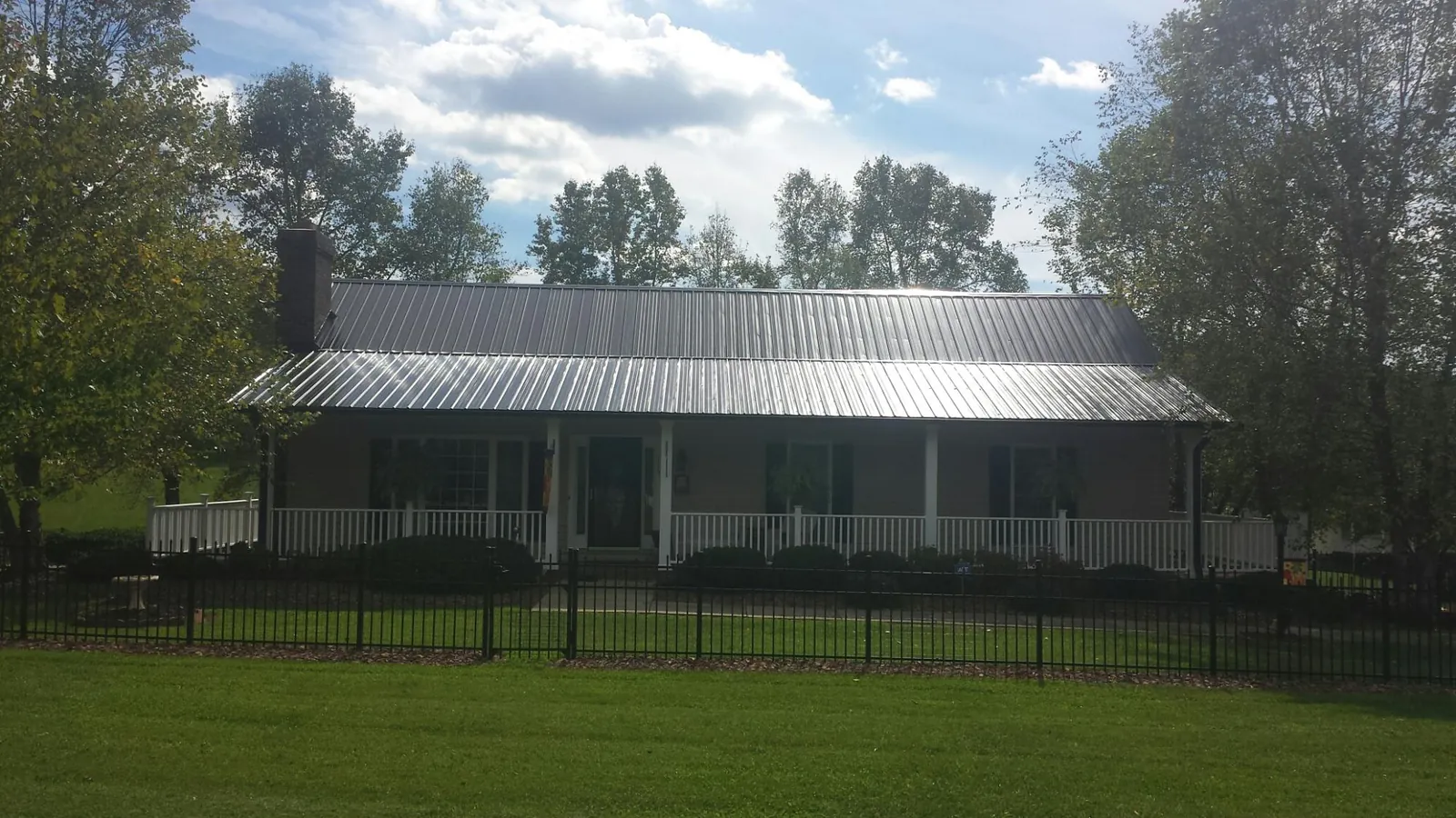 Gray metal roof on a brick ranch with a full width front porch — Gutter Guard Installation work by our crew in Fairborn