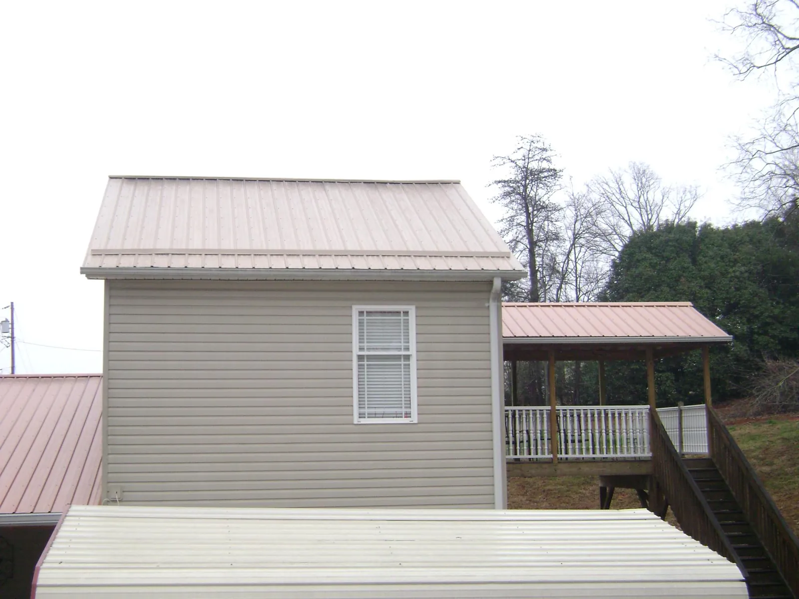Tan metal roofs on a two story addition and attached porch, from a Roof Replacement job in Fairborn