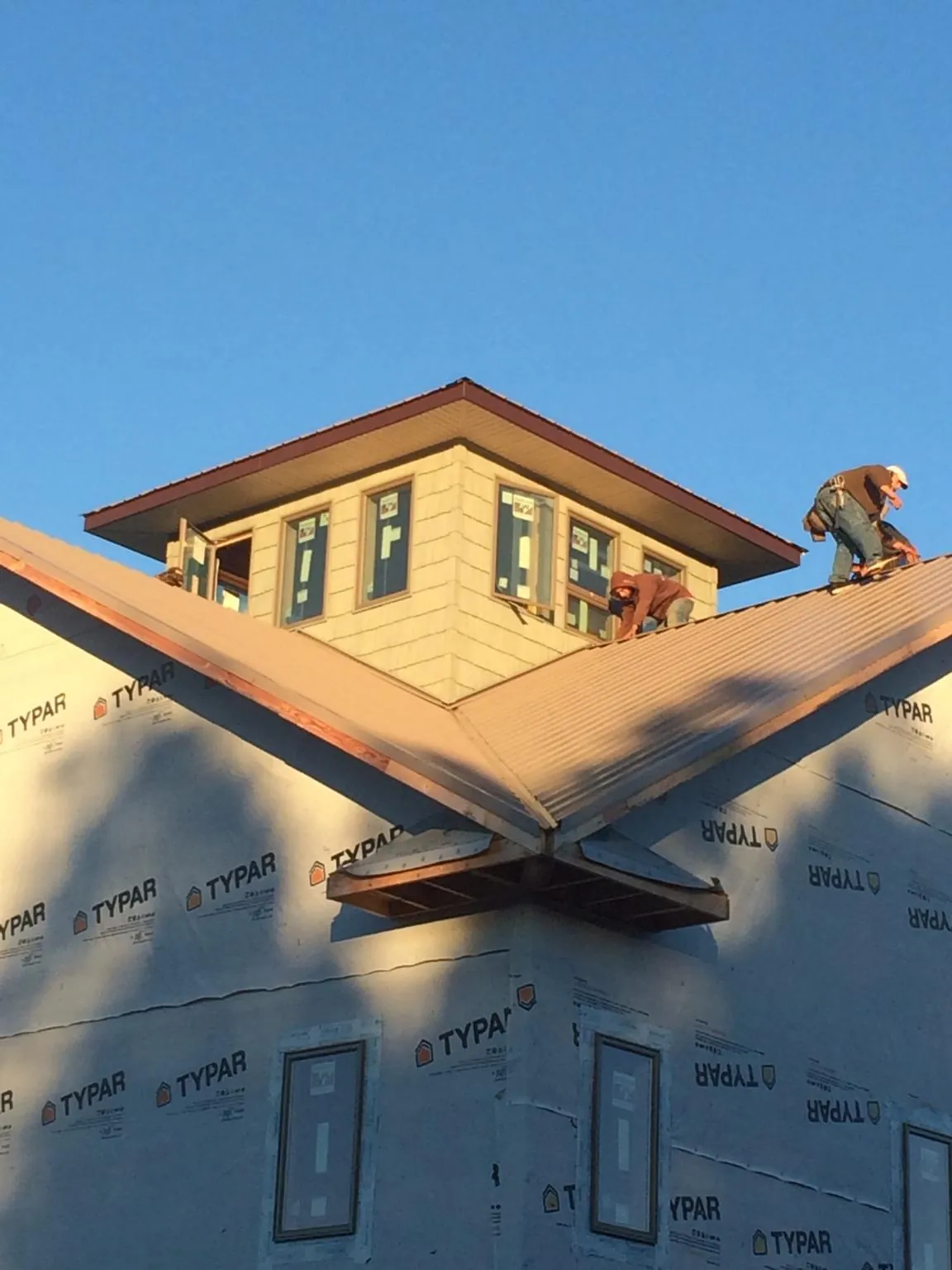 Roofers working around a rooftop cupola on a new metal roof at sunset — Roof Waterproofing in Fairborn by Roofing Brothers